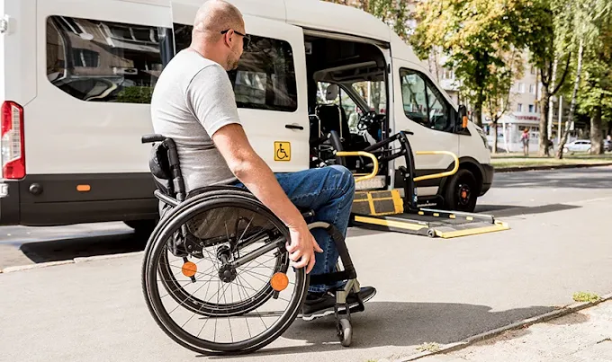 Staff assisting customer to get into a wheelchair taxi